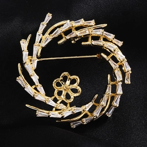 Vue macro d'une broche circulaire dorée sertie de zircons et d'un support en fleur