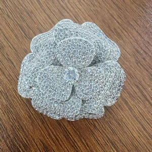 Dettaglio macro della spilla a fiore di camelia con base in metallo argento e zirconi