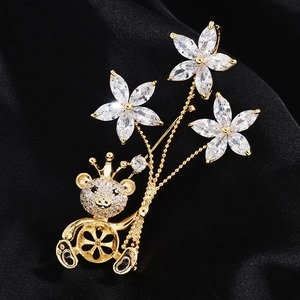 Détail d'une broche ourson dorée avec fleurs en zircon sur fond de soie noire