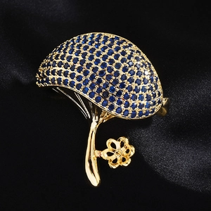 Macro shot of a mushroom brooch with deep blue rhinestones and gold floral detail