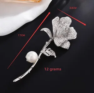 Detailed view of silver rose brooch with micro-pave crystals and white pearl accent