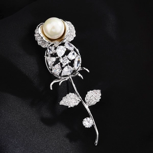 Detail shot of silver rose brooch featuring a large white pearl and clear zircon stones