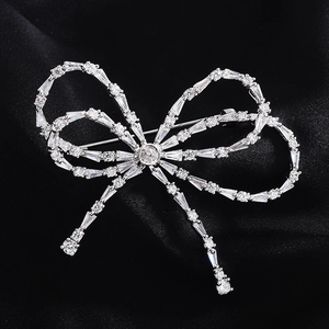 Detailed view of silver bow brooch with zircon inlay on luxury black silk fabric