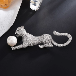 Elegant leopard brooch with white zircons and a large pearl on a dark background