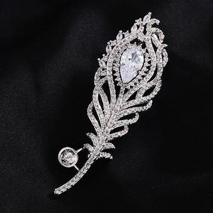 Broche plume de paon en métal argenté avec accents de zircon sur un fond de tissu noir