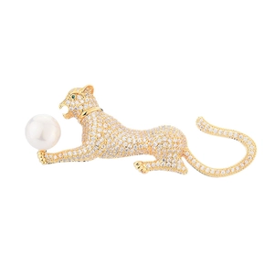 Elegant gold leopard brooch with white zircons and a large round pearl on white background