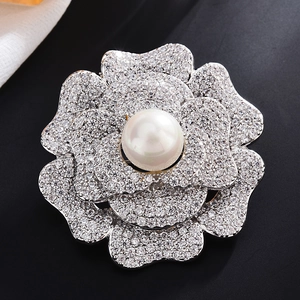Macro di una spilla a camelia argentata con petali di zirconi e perla al centro