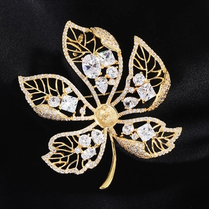 Macro shot of gold leaf brooch featuring hollow veins and faceted zircon inlay on silk