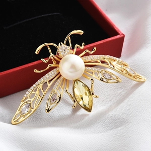Detailed close-up of a luxury bee brooch with white pearl and yellow crystal accents