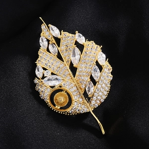 Vue détaillée de la broche feuille dorée avec zircons sur fond de satin noir