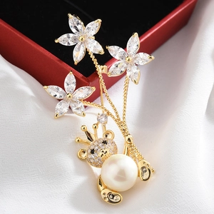 Detail of a gold floral brooch with white pearl and a crowned bear on a gift box