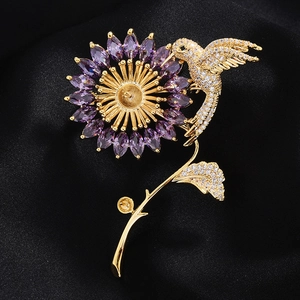 Détail de la broche fleur et colibri dorée avec pierres violettes et zircons incrustés