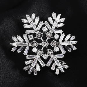 Macro de la broche flocon de neige argentée avec zircons sur soie noire lisse