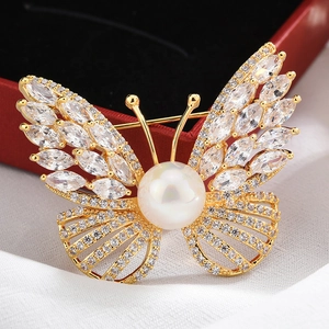 Macro shot of gold butterfly brooch featuring a large pearl and sparkling marquise zircons