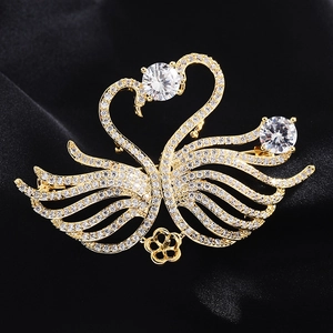 Macro shot of twin swan brooch with gold plating and cubic zirconia inlay