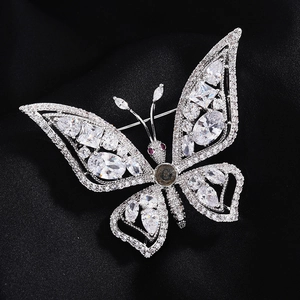 Vue macro d'une broche papillon argentée avec zircons blancs brillants sur tissu en soie noire