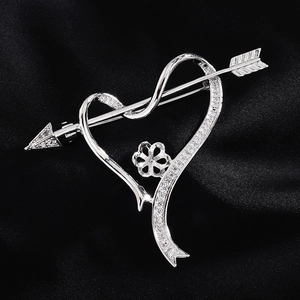 Macro shot of silver heart and arrow brooch base with sparkling zircon micro-inlays