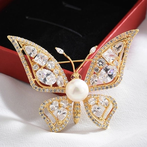 Macro shot of butterfly brooch with white crystals, pearls and gold plating detail