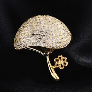 Detailed close-up of a gold-plated mushroom brooch base with zircon and satin background