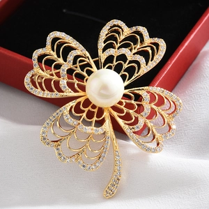 Macro shot of clover brooch with a large white pearl and sparkling crystals in gold finish