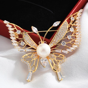 Detailed macro of gold butterfly brooch with large pearl and sparkling zircon stones