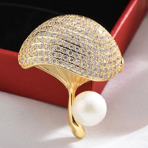 Macro shot of gold ginkgo leaf brooch with white crystals and round pearl detail