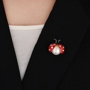 Detail of ladybug magnetic brooch with pearl and red enamel on black blazer