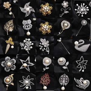 Set van 25 elegante broches met zirkonia en parels op een zwarte satijnen ondergrond