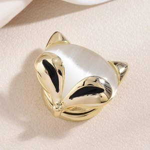 Élégante broche renard dorée avec pierre œil de chat blanc sur fond de cuir beige de luxe