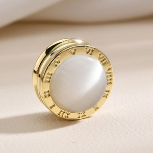 Macro shot of gold Roman numeral magnetic brooch with silk-gloss white stone inlay