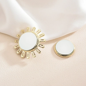 Elegant gold sunburst magnetic brooch with white shell center on silk background