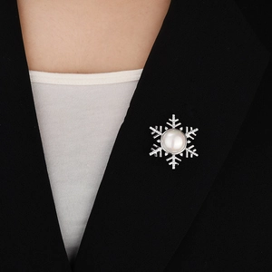 Detail view of a pearl snowflake brooch on a black suit lapel with magnetic clasp