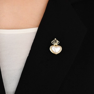 Detail of a gold crown heart pearl brooch pinned on a black suit jacket lapel