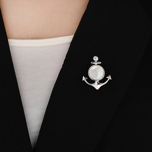 Détail de la broche ancre argentée avec perle et zircon sur un blazer élégant