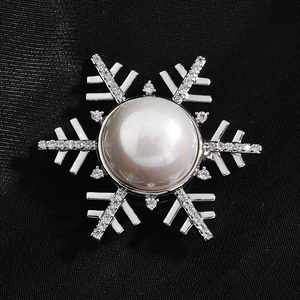 Sparkling snowflake magnetic brooch with pearl center and crystals on black fabric