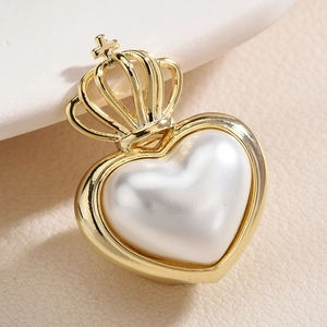Elegant gold crown heart brooch pin with white pearl inlay on a leather surface