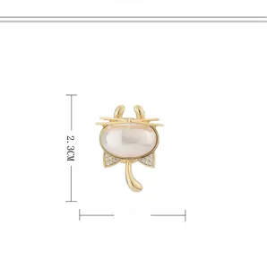 Dettaglio di una spilla magnetica a gatto dorata con perle e zirconi incastonati
