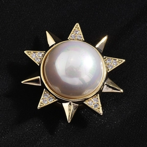 Elegant gold sunflower brooch with large white pearl and crystals on black fabric