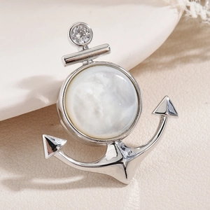 Broche ancre élégante avec nacre blanche et cristal brillant sur fond beige texturé