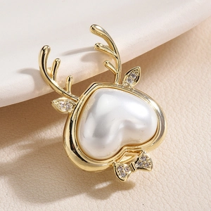 Elegant gold antler heart pearl brooch with a sparkling bow on a white ceramic base