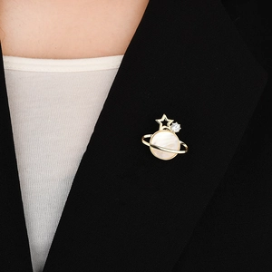 Eleganter Saturn-Magnet-Brosche mit Muschel und Goldstern auf einem schwarzen Anzug