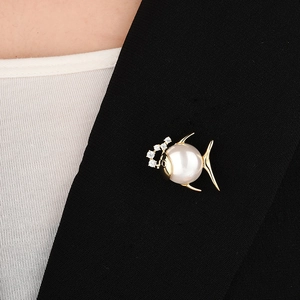 Détail de la broche poisson avec perle blanche et métal doré sur veste de costume