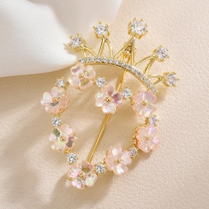 Broche couronne et cœur dorée avec fleurs roses et strass sur fond en cuir texturé