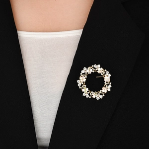 Elegant gold flower wreath brooch with zircon and pearls on a black suit lapel