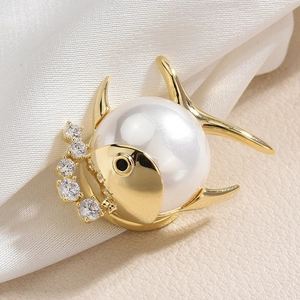 Broche poisson dorée élégante avec grande perle et zircons sur fond de soie douce