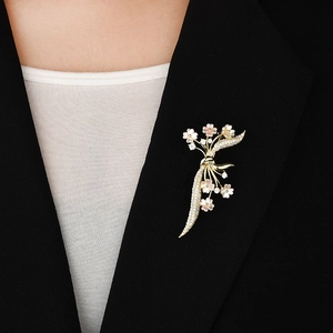 Elegante spilla a fiore dorato con petali in conchiglia rosa e zirconi su una giacca blazer