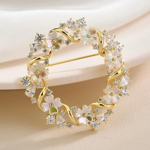 Elegant floral wreath brooch with golden finish and sparkling zircon stones on white silk
