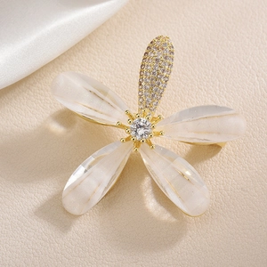 Elegant gold flower brooch with cubic zirconia and resin petals on silk background