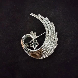 Detailed macro view of a silver alloy feather brooch featuring pave-set rhinestones