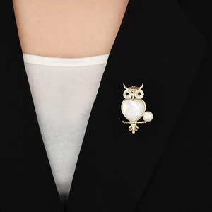 Elegant owl brooch with white shell heart and sparkling zircons on a black blazer
